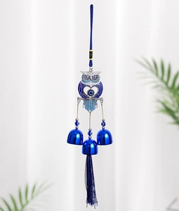 Detail of owl metal wind chime with Evil Eye nazar elements and blue hanging bells