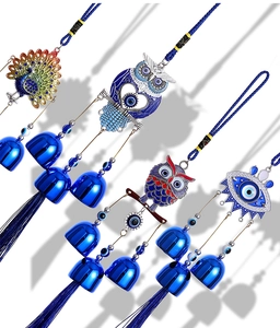 Detail of blue evil eye wall hangings with metal bells, peacocks, and owls on white background