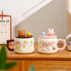 Detail of cute bear and rabbit ceramic mugs with wavy handles and decorative lids