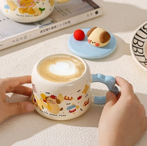 Top-down view of a cream ceramic mug with blue cloud handle and cute dog illustration