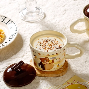 Detailed view of ceramic bear mug with wooden coaster and lid in a cozy tea setting