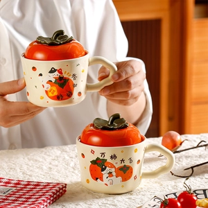 Detail of ceramic mug featuring orange persimmon lid and cute cat illustration