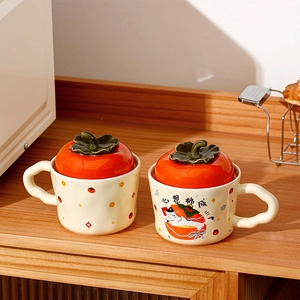 Detailed view of creative persimmon ceramic mugs with a kitten design and red lids