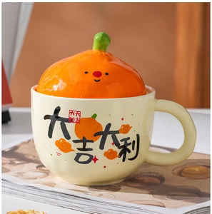 Close-up of ceramic mug set featuring orange-shaped lid and festive calligraphy text