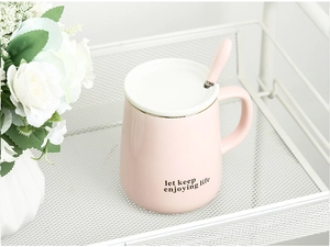 Pink ceramic mug with lid and spoon featuring gold trim and inspirational text
