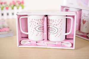 Detailed gift box set featuring two ceramic mugs with heart patterns and spoons