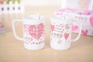 Close-up of two white ceramic mugs with cute fish patterns and matching spoons