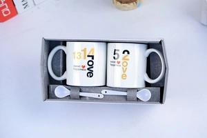 Close-up of ceramic couple mugs with 520 1314 print and spoons in a gift box