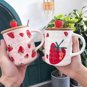 Cute strawberry ceramic mug set with wooden lid and spoon held in hand