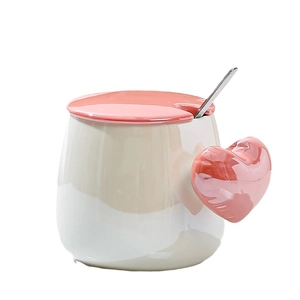Cute ceramic mug set with pink heart-shaped handle and metal spoon in cream and coffee tones