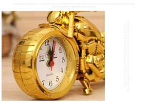 Macro shot of gold motorcycle-shaped quartz alarm clock showing detailed wheel dial