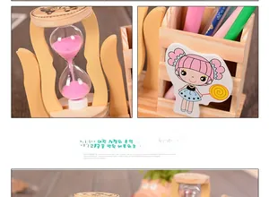 Detail of wooden pencil holder with pink sand hourglass and cartoon girl motif
