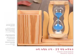 Macro detail of wooden pen holder with blue sand hourglass on a dark textured desk