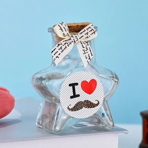 Star-shaped glass bottle with cork stopper, decorative white ribbon and round sticker