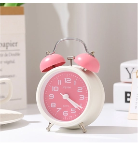 Détail d'un réveil à double cloche rose avec cadre en métal blanc sur le chevet