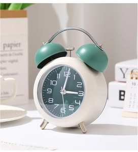 Vue détaillée du réveil rétro à double cloche crème et vert foncé sur une table