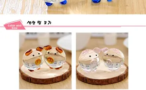 Detailed view of handmade glass pig figurines in orange and pink on a wooden stand