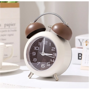 Vue détaillée d'un réveil rétro à double cloche crème et marron sur un bureau épuré