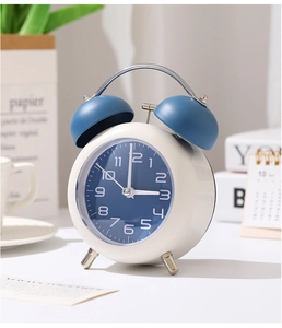 Détail d'un réveil à double cloche minimaliste sur un bureau avec un décor matinal chaleureux