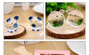 Detailed view of handmade crystal glass pig ornaments on a natural wood tray
