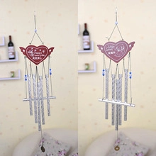 Detail of heart-shaped ceramic wind chimes with metal tubes and romantic blessings