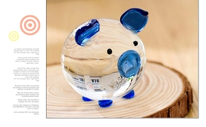 Detailed view of clear crystal glass pig figurine with blue accents on a wood slice