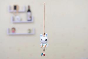 Detail of white ceramic bunny wind chime with carrot pattern and colorful beads