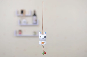 Close-up of ceramic bunny wind chime with floral ears, carrot print, and wooden beads