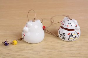 Macro view of ceramic lucky cat wind chimes with braided rope and decorative beads