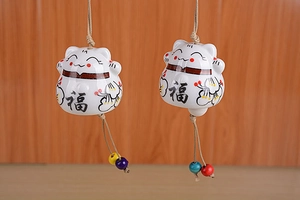Detail of white ceramic lucky cat wind chimes with floral patterns and colorful wooden beads