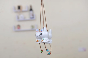 Detailed close-up of cartoon ceramic rabbit pendants with colorful beads and hanging ropes