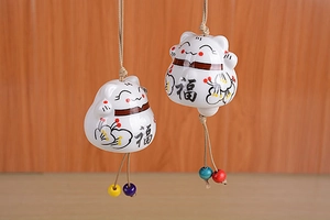 Close-up of Japanese ceramic lucky cat wind chime with wood beads and red floral details
