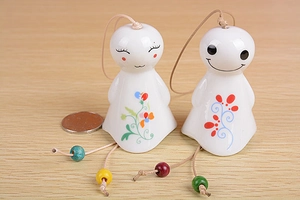 Detailed view of two cute ceramic sunny dolls with colorful floral patterns and bell beads
