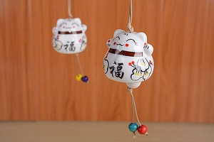 Detail of ceramic Japanese Maneki Neko wind chime with lucky Fu character and plum blossoms
