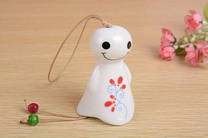 Close-up of a white ceramic wind chime featuring a cute smiley face and floral patterns