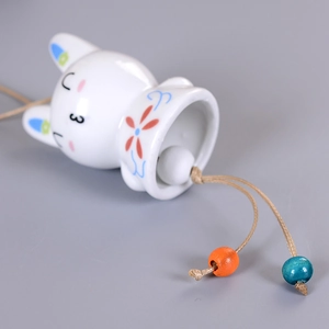 Handcrafted white ceramic cat wind chime with blue floral patterns and brown hanging cord
