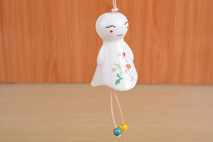 Close-up of ceramic sun doll wind chime with cute smiling face and floral pattern