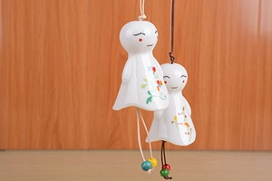 Detail of two handmade ceramic wind chimes with hand-painted patterns and colorful beads