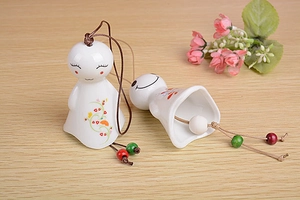 Detail of two white ceramic sun dolls wind chimes with colorful floral vine patterns