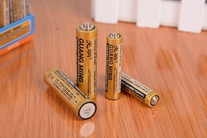 Detailed view of four AA 1.5V alkaline batteries on a textured wooden surface