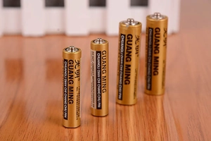 Close-up of four Guang Ming 1.5V alkaline batteries on a wooden surface detail