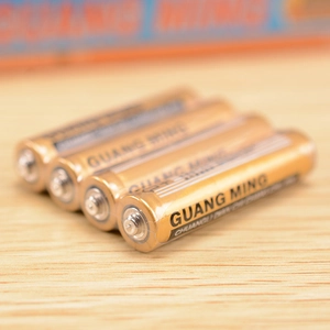 Set of four 1.5V GUANG MING AAA dry batteries for clocks and toys on wooden surface