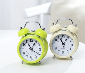 Detailed macro view of classic twin bell metal alarm clock in bright green and ivory white
