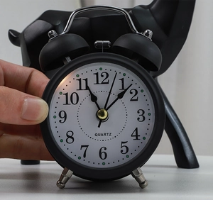 Close-up of a classic black twin bell alarm clock featuring a white dial and quartz movement
