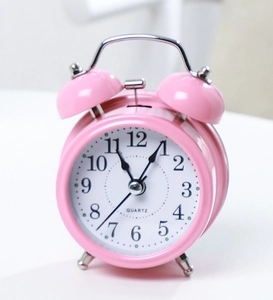 Detail of pink metal twin bell alarm clock with quartz movement and numeric dial