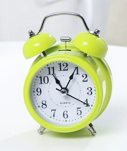 Detail view of a classic lime green twin bell alarm clock with quartz movement dial