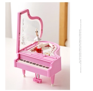 Detail of pink grand piano music box featuring a spinning ballerina and floral mirror