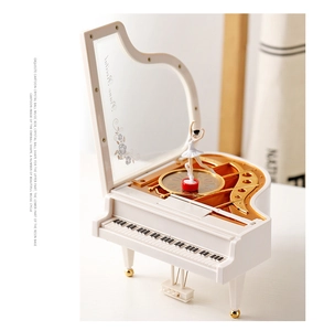 Detailed side view of white piano music box with rotating ballerina and gold movement