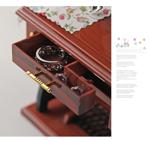 Macro detail of a vintage sewing machine music box drawer containing a gemstone ring