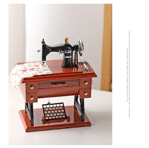Detail of vintage sewing machine music box with miniature scissors and floral fabric trim